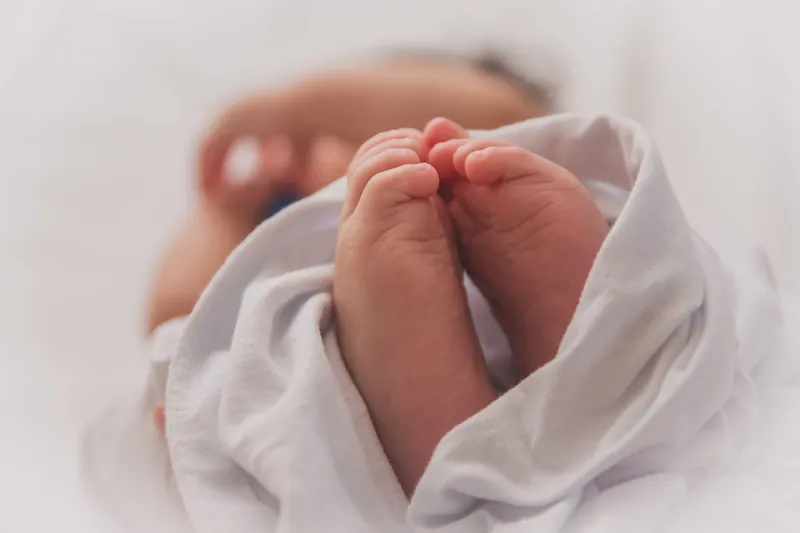 Twee babyvoetjes steken uit een witte doek